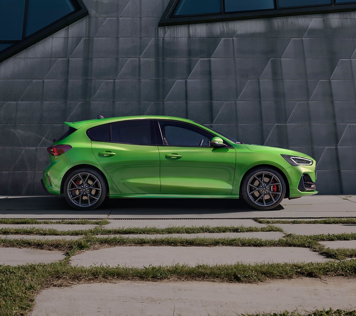 Ford Focus ST in Grün. Seitenansicht, vor einer grauen Wand stehend.